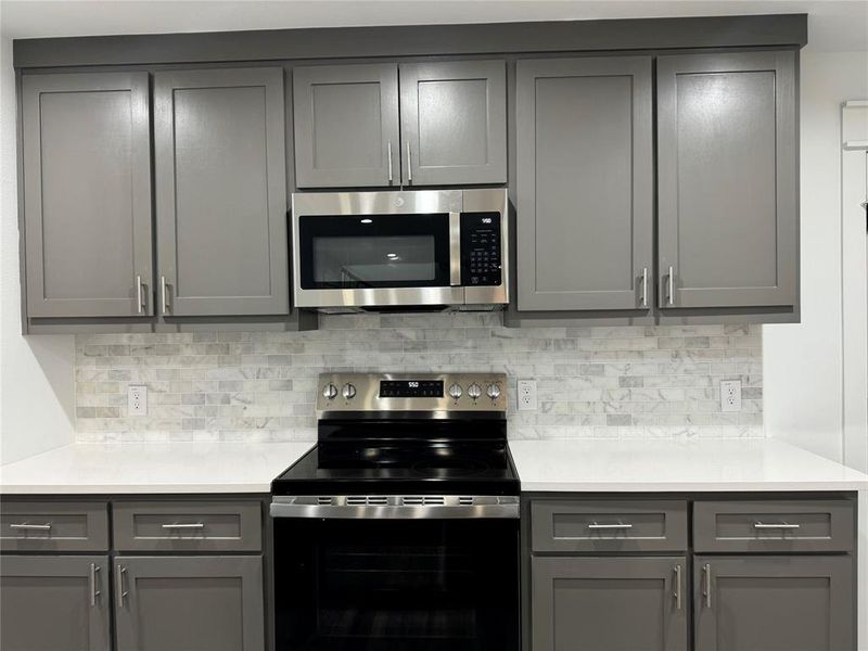 Kitchen featuring appliances with stainless steel finishes and gray cabinetry