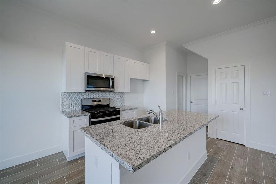 Please visit 6410 Leopold Star Lane to see the builder's standard finishes. The kitchen sits at the heart of the home between the living and dining areas. The door shown beneath the stairs conceals a sizable pantry, while the door to the left offers a well-sized powder room.