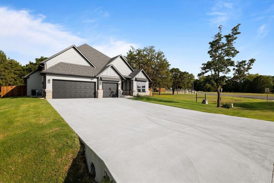 View of front of house with a front lawn, a garage, and central air condition unit