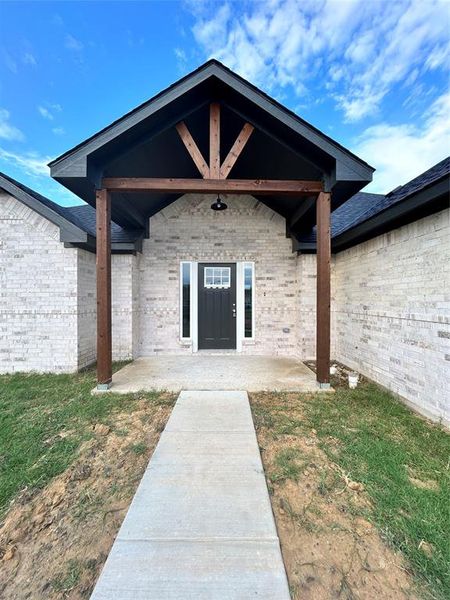 Property entrance featuring a patio and a lawn