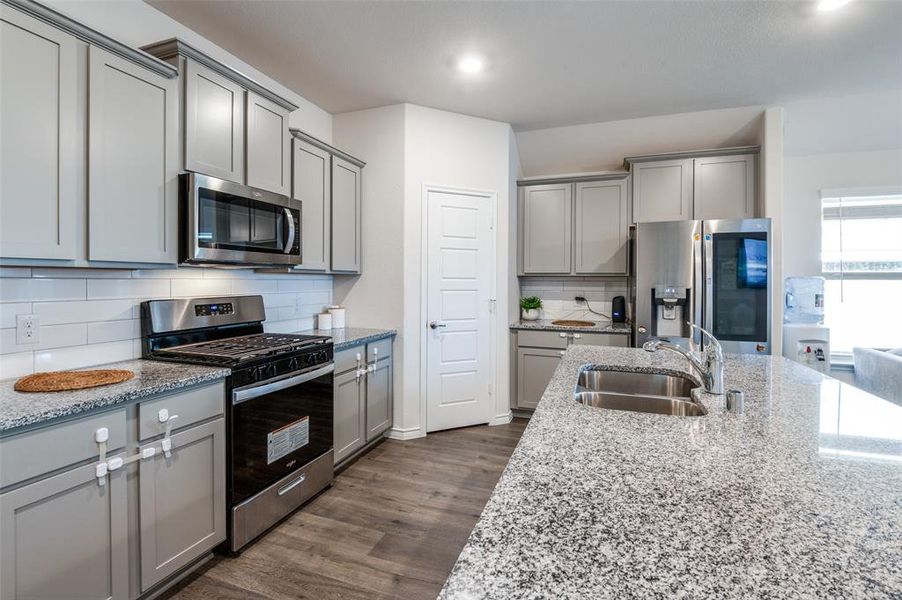 Kitchen with light stone countertops, appliances with stainless steel finishes, sink, and dark hardwood / wood-style floors