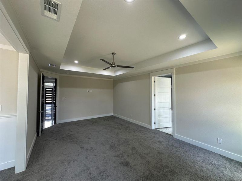 Master Bedroom with attached office featuring ceiling fan, a raised ceiling, and dark carpet