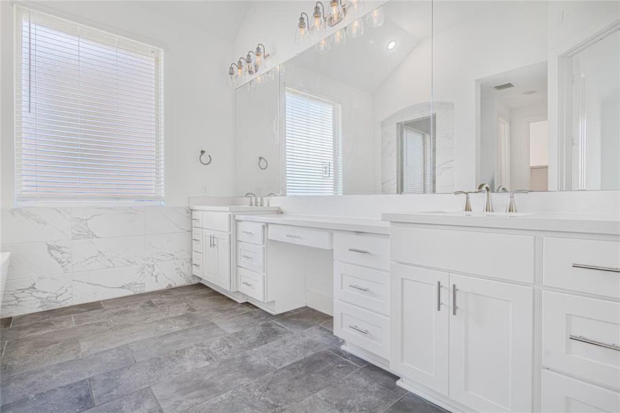 In your primary bathroom,you're greeted by elegant tile flooring and pristine countertops, complemented by custom white cabinetry offering ample storage for all your essentials.