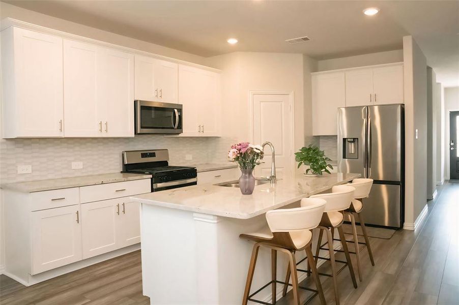 Kitchen featuring appliances with stainless steel finishes, a kitchen island with sink, sink, and white cabinets