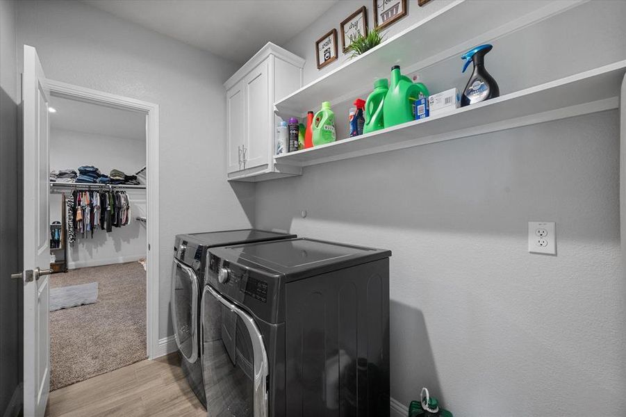 Laundry area with cabinets, light hardwood / wood-style flooring, and washer and dryer