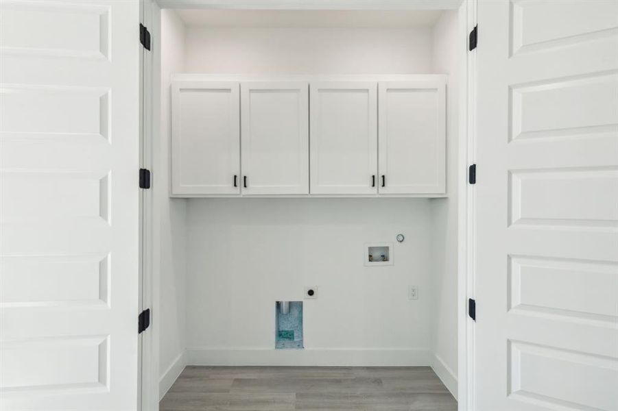 Washroom with washer hookup, hookup for an electric dryer, light hardwood / wood-style floors, and cabinets