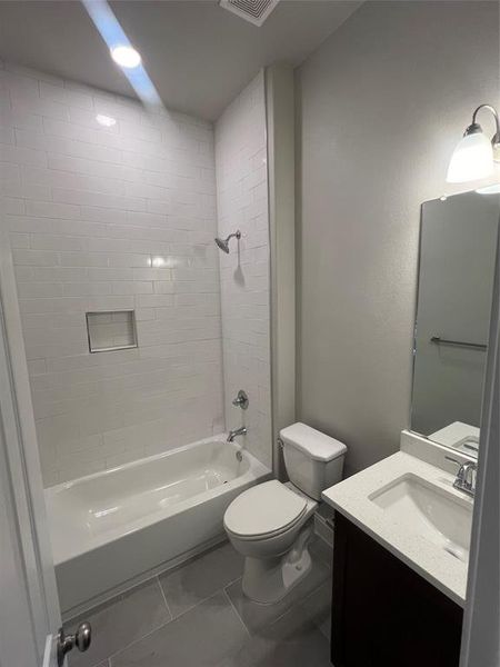 Full bathroom featuring tile patterned flooring, tiled shower / bath combo, vanity, and toilet