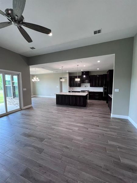 Unfurnished living room with sink, hardwood / wood-style flooring, and ceiling fan with notable chandelier