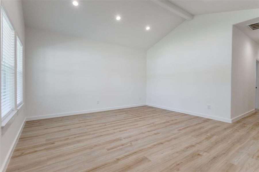 Unfurnished room with vaulted ceiling with beams and light hardwood / wood-style flooring