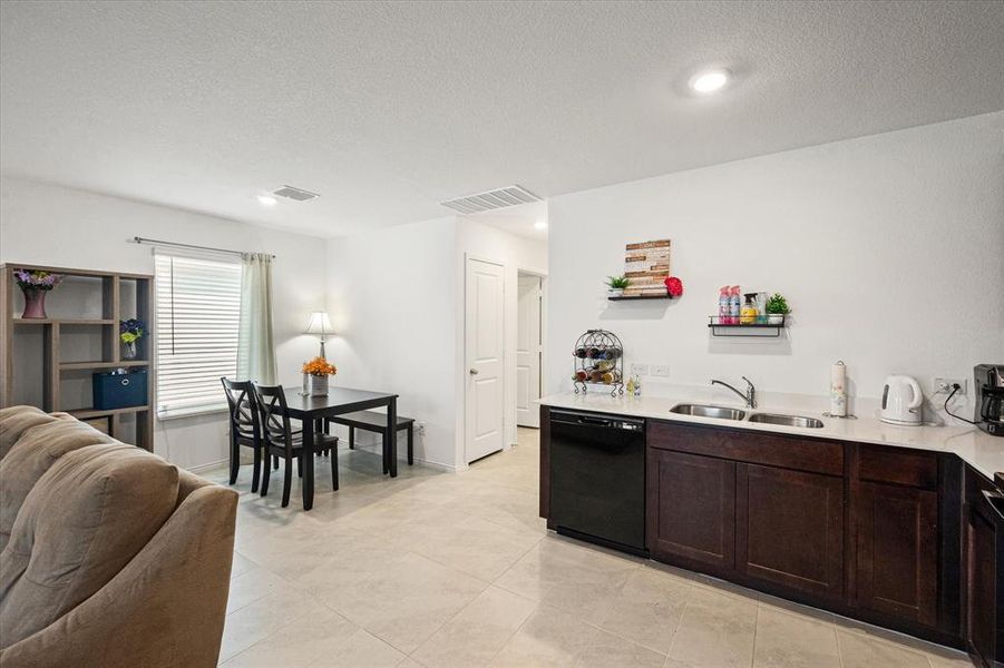 Kitchen featuring dishwasher, sink, dark brown cabinets, and a textured ceiling