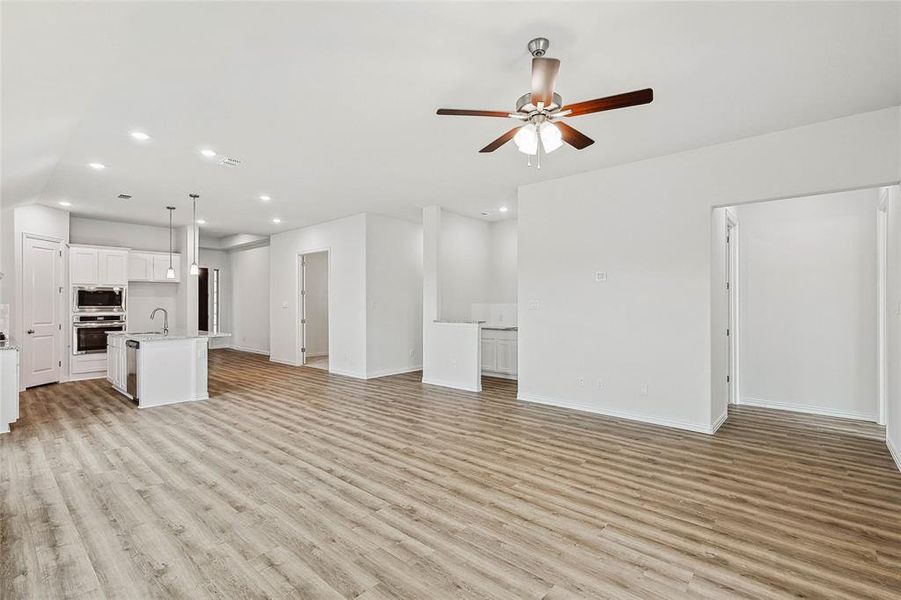 Unfurnished living room featuring sink, ceiling fan, and light hardwood / wood-style flooring