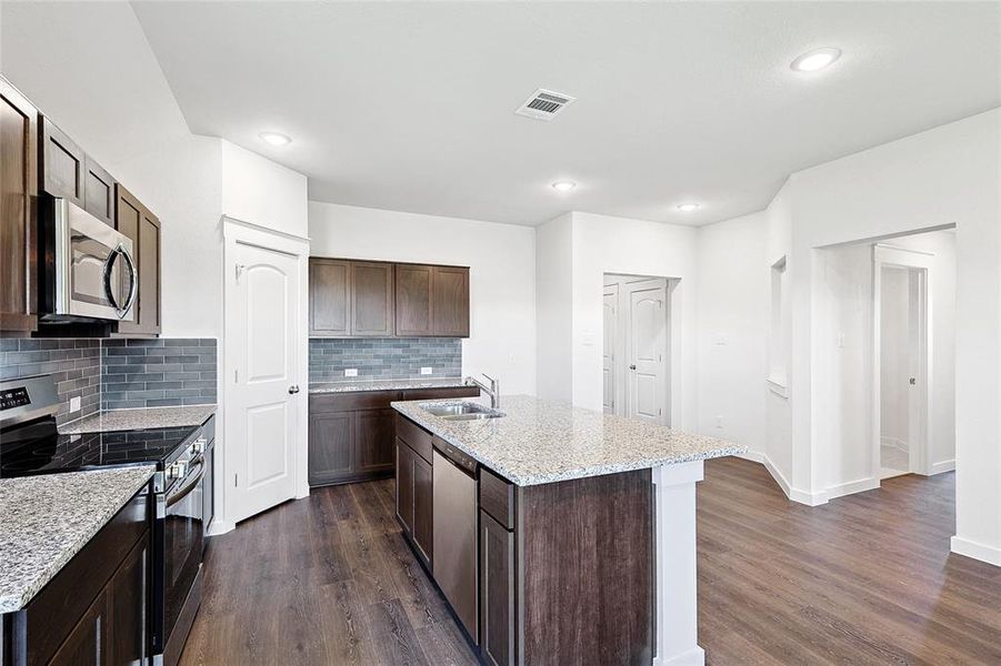 Kitchen with appliances with stainless steel finishes, an island with sink, sink, and dark hardwood / wood-style floors