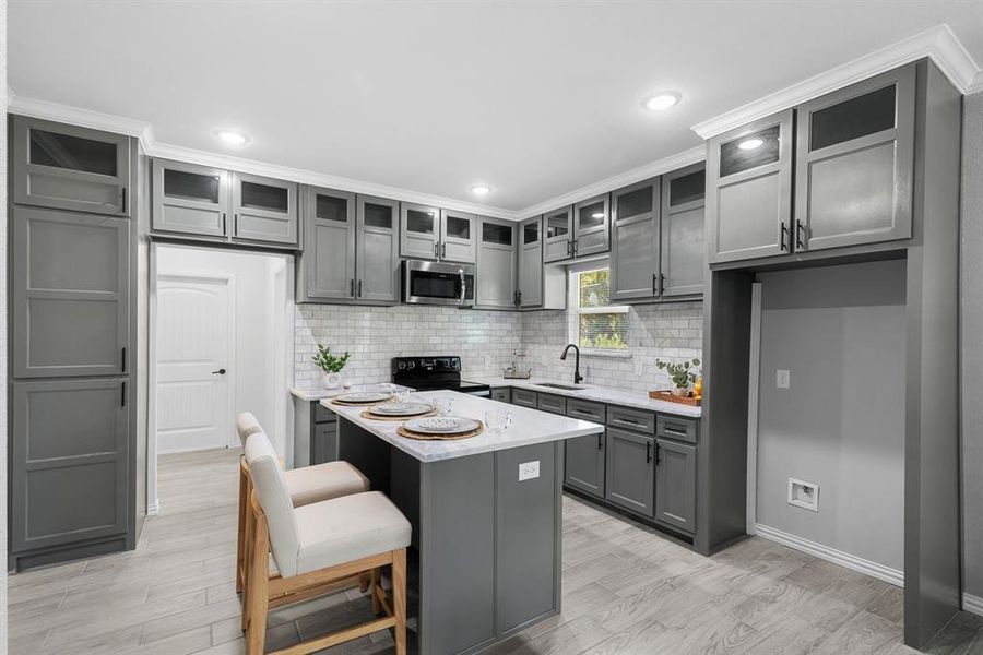 Kitchen featuring a breakfast bar, sink, light hardwood / wood-style floors, backsplash, and black electric range oven