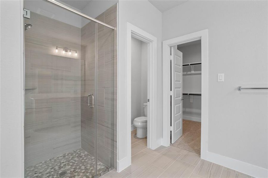 This additional view of the primary bath showcased the large walk-in shower with tile surround, privacy toilet area, and spacious walk-in closet.