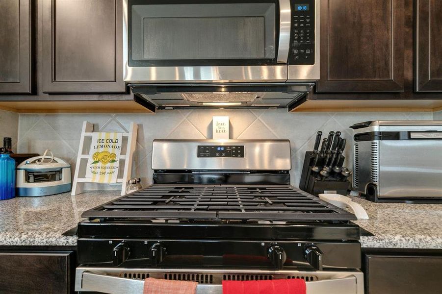 Kitchen featuring dark brown cabinetry, decorative backsplash, and stainless steel appliances