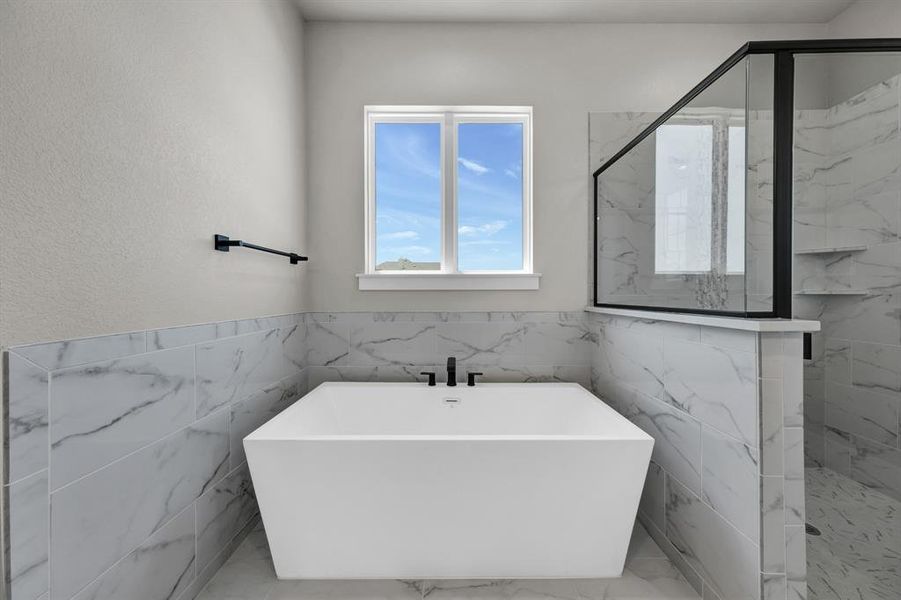 Bathroom featuring tile walls, tile flooring, and separate shower and tub