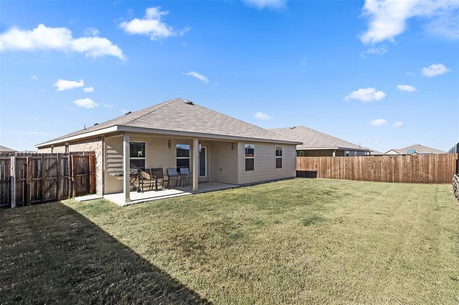 Rear view of property featuring a lawn and a patio