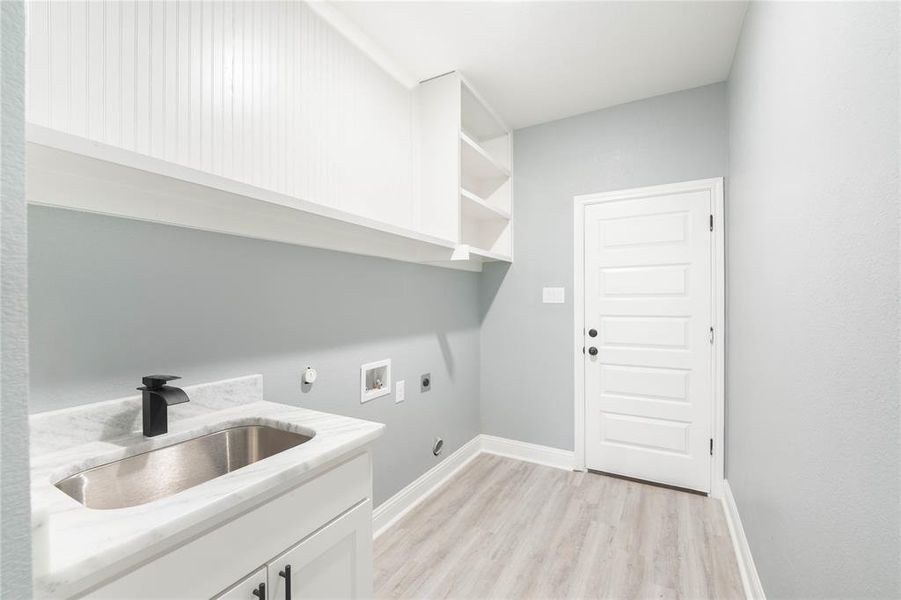 Laundry area with hookup for an electric dryer, cabinets, light hardwood / wood-style floors, sink, and washer hookup