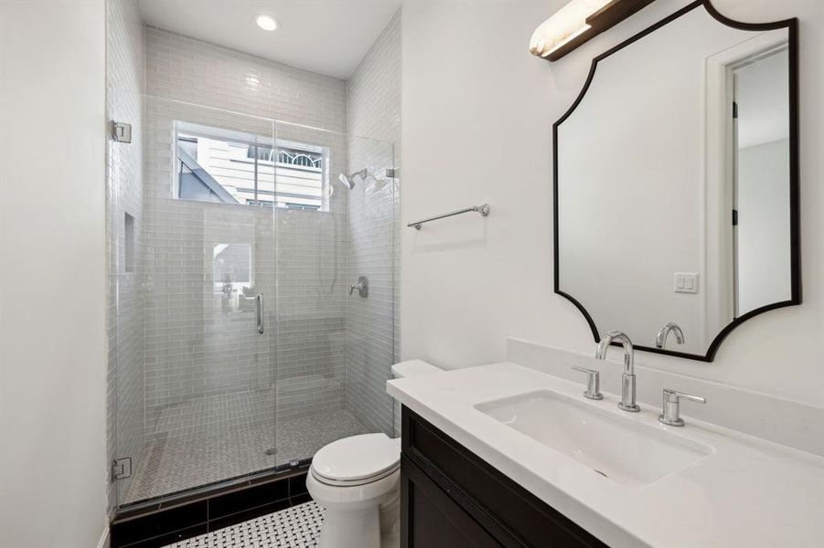 Private ensuite bath serving previously photographed bedroom with quartz countertops and walk-in shower. Notice all of the beautiful tile selections.