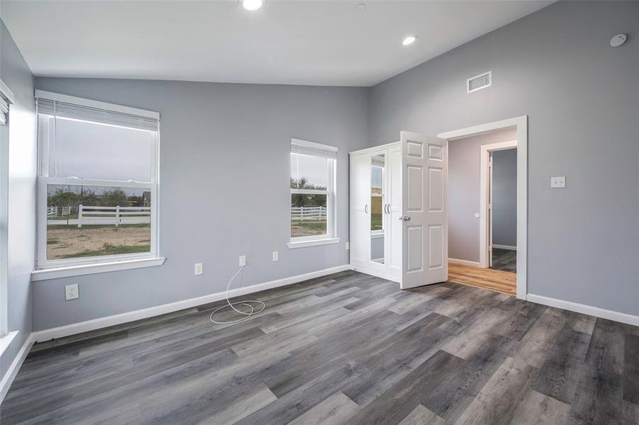 Unfurnished bedroom with vaulted ceiling and dark hardwood / wood-style flooring