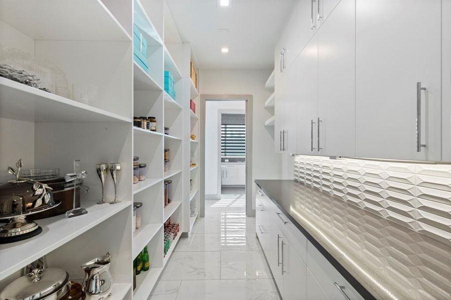 A modern and very functional open ended pantry with floor to ceiling storage easily doubles as a catering kitchen. Pocket doors on each end keep the space contained when needed.