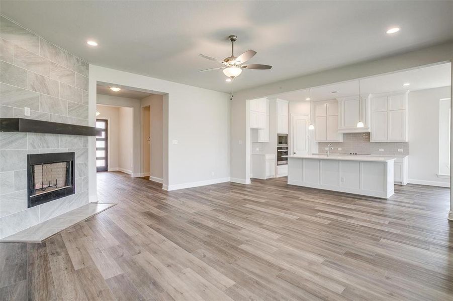 Unfurnished living room featuring a fireplace, light hardwood / wood-style flooring, ceiling fan, and sink