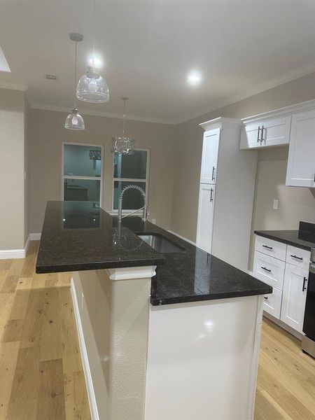 Kitchen with light wood-type flooring, hanging light fixtures, and a center island