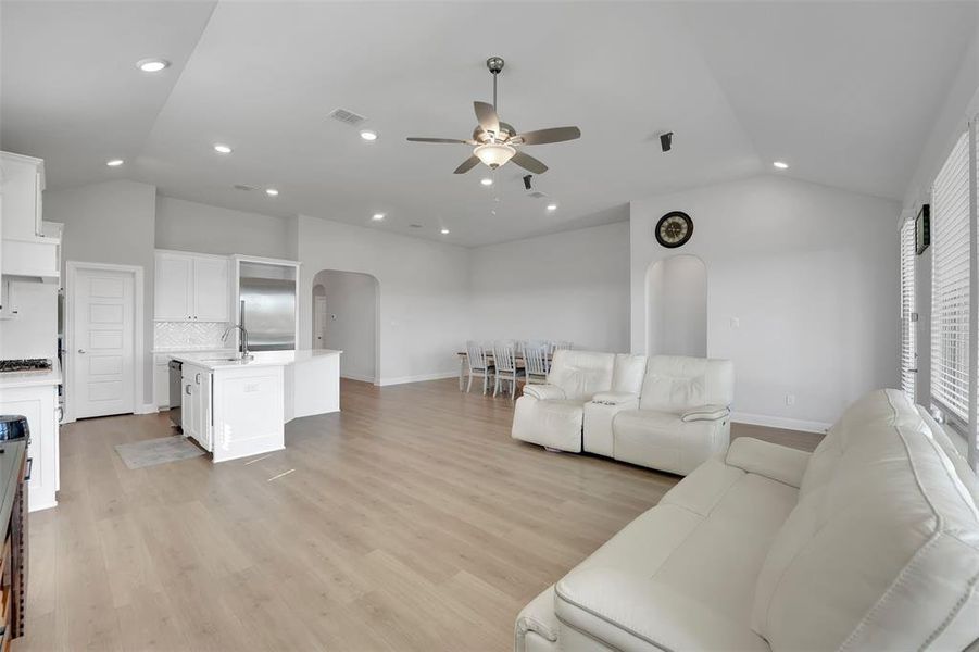 Living room with lofted ceiling, ceiling fan, and light hardwood / wood-style flooring