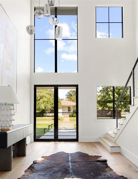 Foyer with a high ceiling, light hardwood / wood-style floors, and a notable chandelier