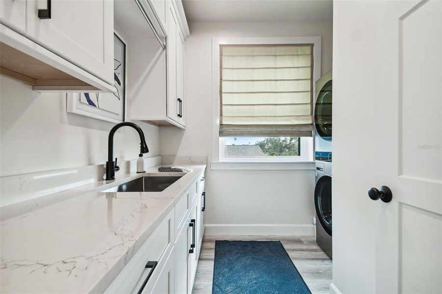Laundry room with sink, cabinets and picture window for natural light.