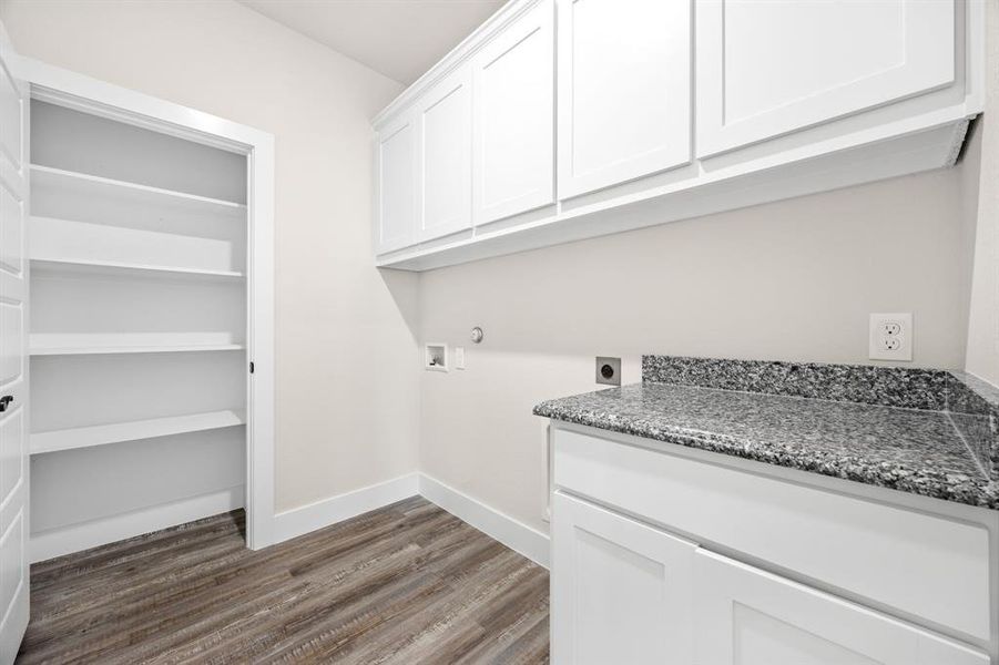 Clothes washing area with washer hookup, electric dryer hookup, hardwood / wood-style floors, and cabinets