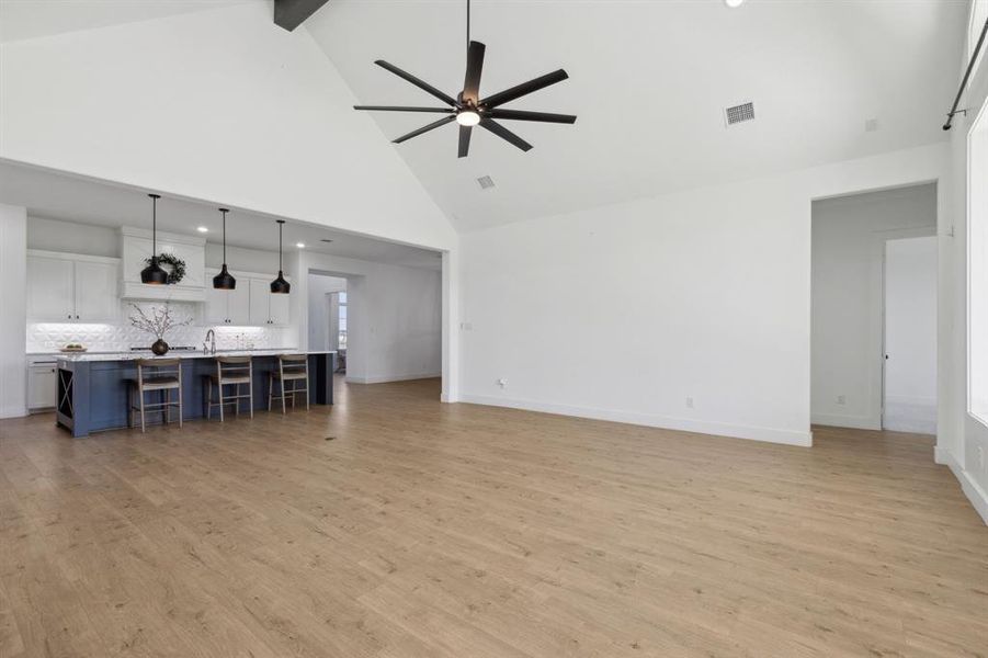 Living room with ceiling fan, beamed ceiling, light hardwood / wood-style flooring, and high vaulted ceiling