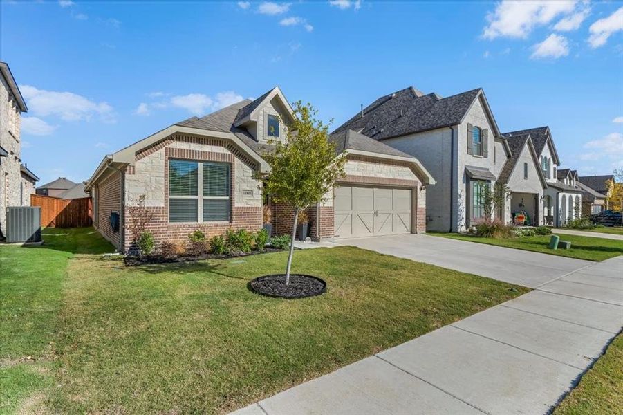 View of front of property with central air condition unit, a front yard, and a garage