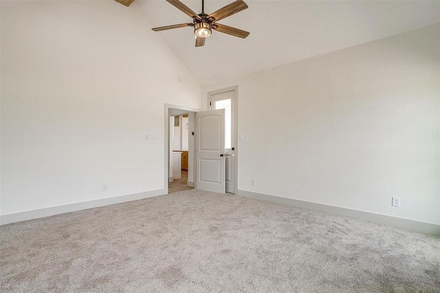 Carpeted spare room with ceiling fan and high vaulted ceiling