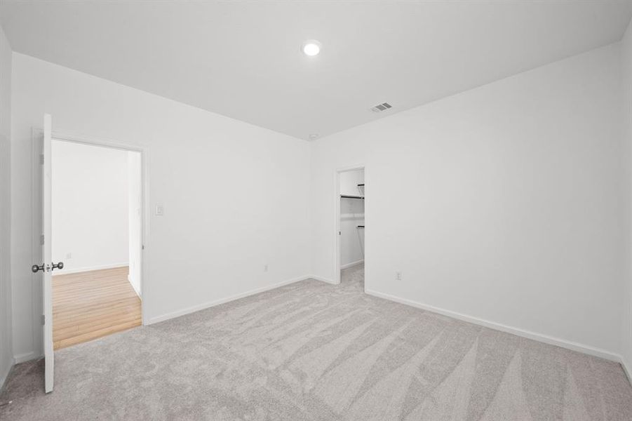 Bedroom 3 with walk-in closet space with Carpet and white wood blinds.