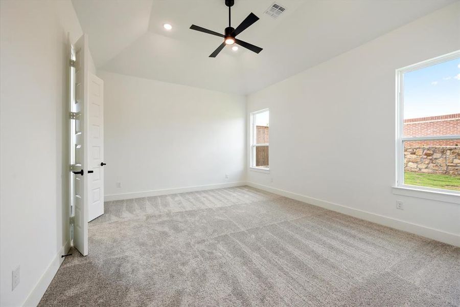 Carpeted spare room featuring lofted ceiling and ceiling fan