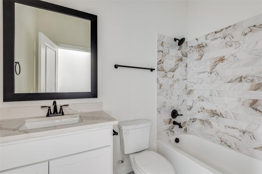 Full bathroom featuring tiled shower / bath, toilet, and vanity