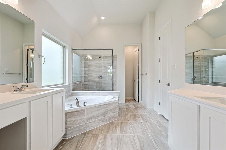 Bathroom featuring lofted ceiling, shower with separate bathtub, and vanity