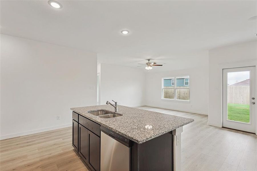 Kitchen featuring a center island with sink, ceiling fan, dishwasher, light hardwood / wood-style floors, and sink