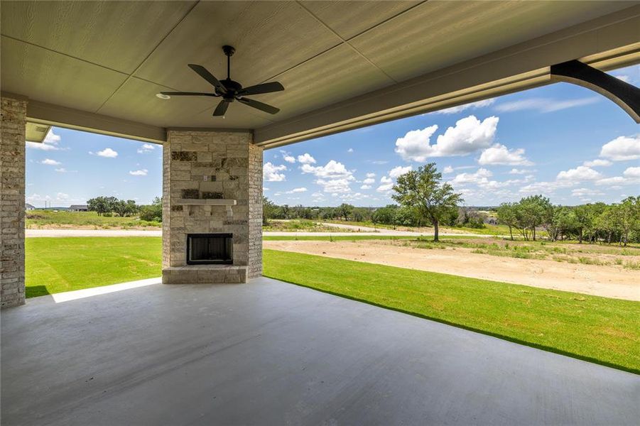 View of patio featuring an outdoor stone fireplace and ceiling fan