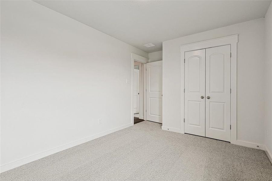 Unfurnished bedroom featuring light carpet and a closet