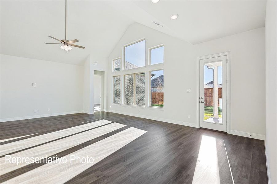 Unfurnished living room featuring high vaulted ceiling, ceiling fan, and dark wood-type flooring