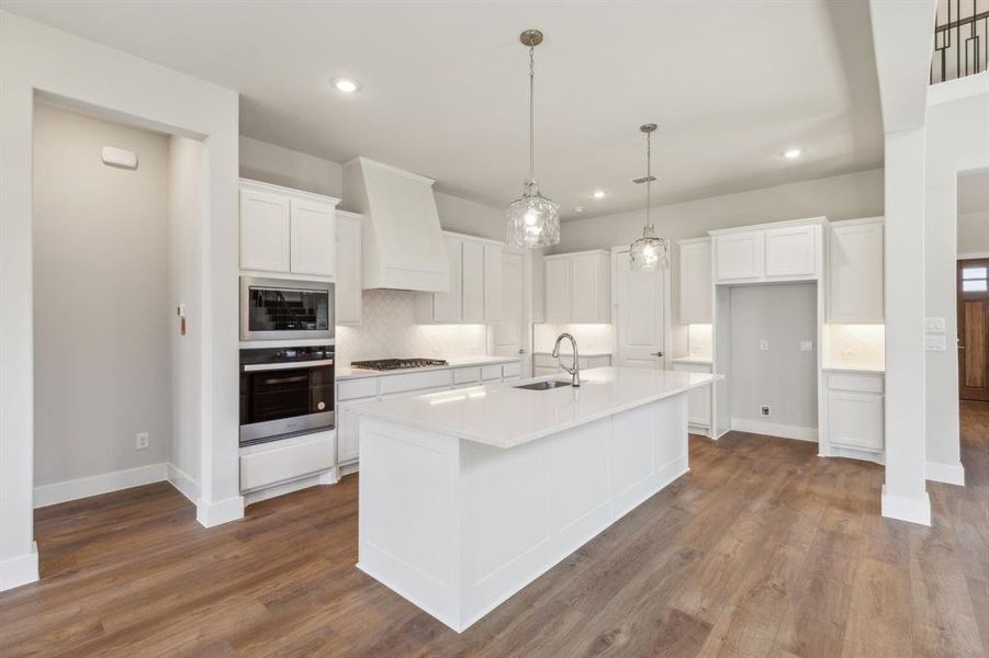 Kitchen with white cabinets, a kitchen island with sink, and wood-type flooring