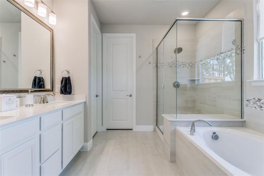 Bathroom featuring vanity, tile flooring, and shower with separate bathtub