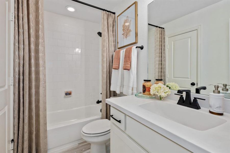 Full bathroom featuring vanity, hardwood / wood-style floors, shower / bath combination with curtain, and toilet