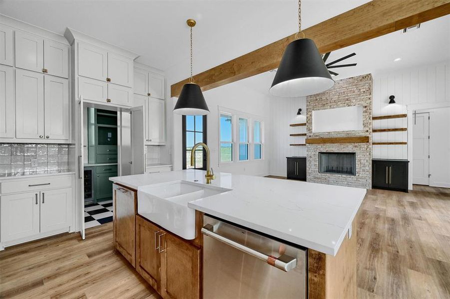 Kitchen with a stone fireplace, stainless steel appliances, beamed ceiling, and light hardwood / wood-style floors