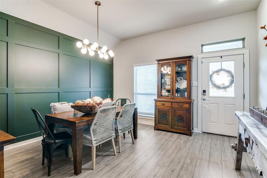 Dining space featuring a notable chandelier, lofted ceiling, and light hardwood / wood-style floors