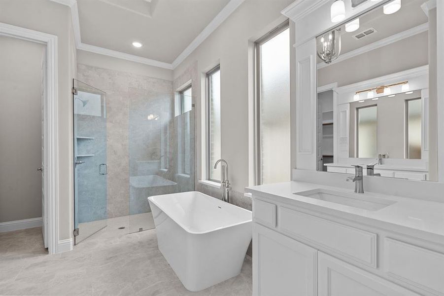 Bathroom featuring vanity, separate shower and tub, and ornamental molding.Not actual home. Previous built example.