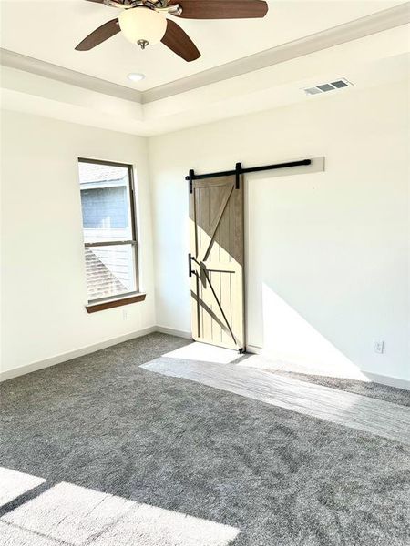 Spare room with a barn door, carpet, and ceiling fan