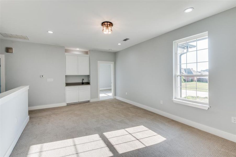 Unfurnished living room featuring plenty of natural light, sink, and light carpet